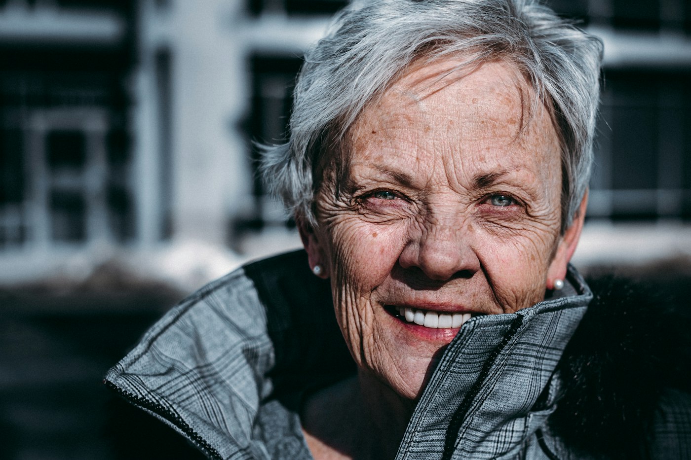 Une dame âgée aux cheveux gris sourit.
